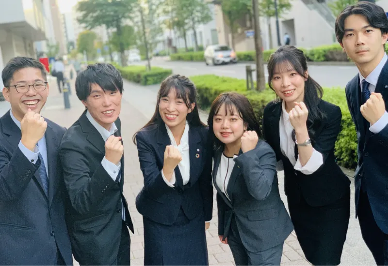 スーツを着た男女がガッツポーズしている写真
